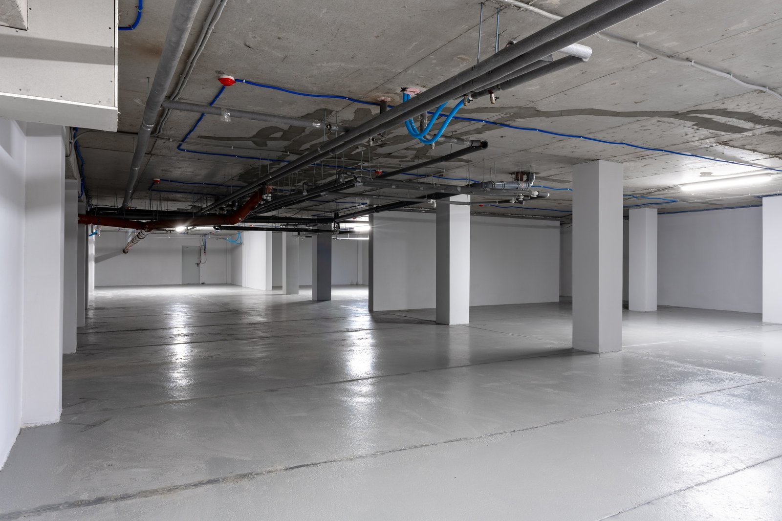 Empty underground parking garage with exposed pipes and clean concrete floors in a modern structure