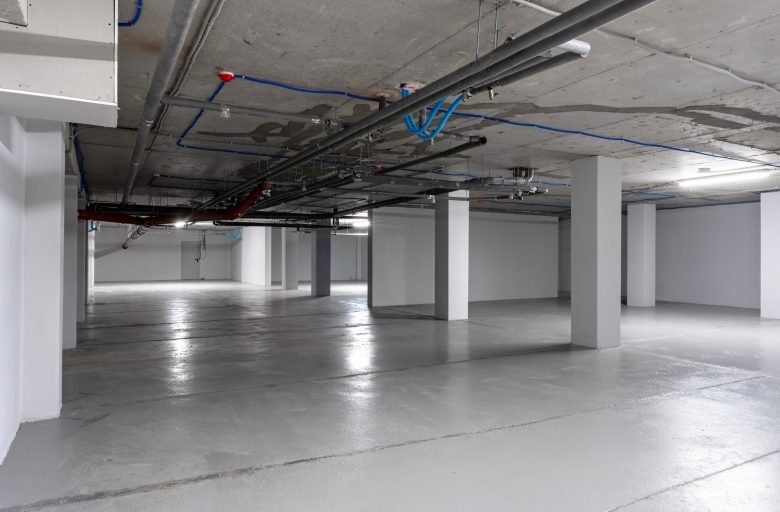 Empty underground parking garage with exposed pipes and clean concrete floors in a modern structure